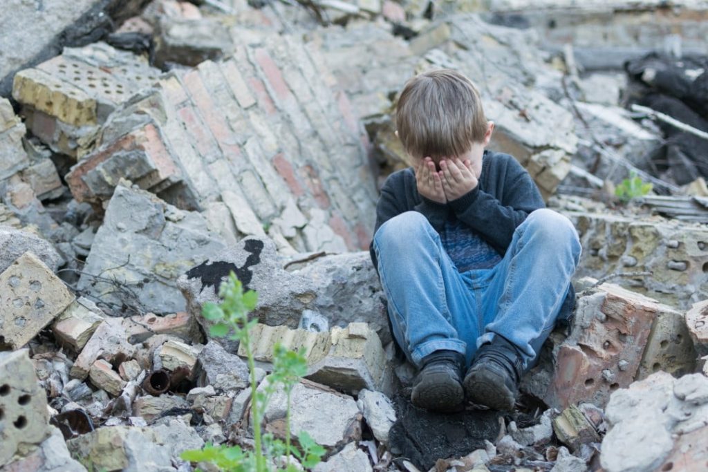 boy crying in remains of storm-destroyed home