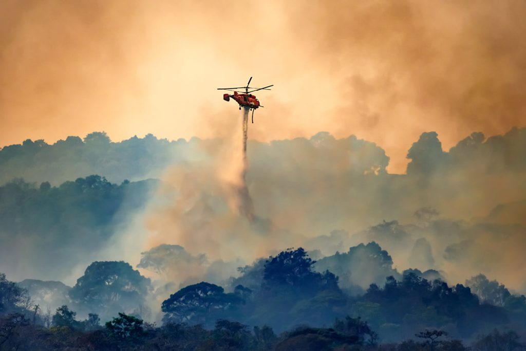 Helicopter drops water on burning wildfires